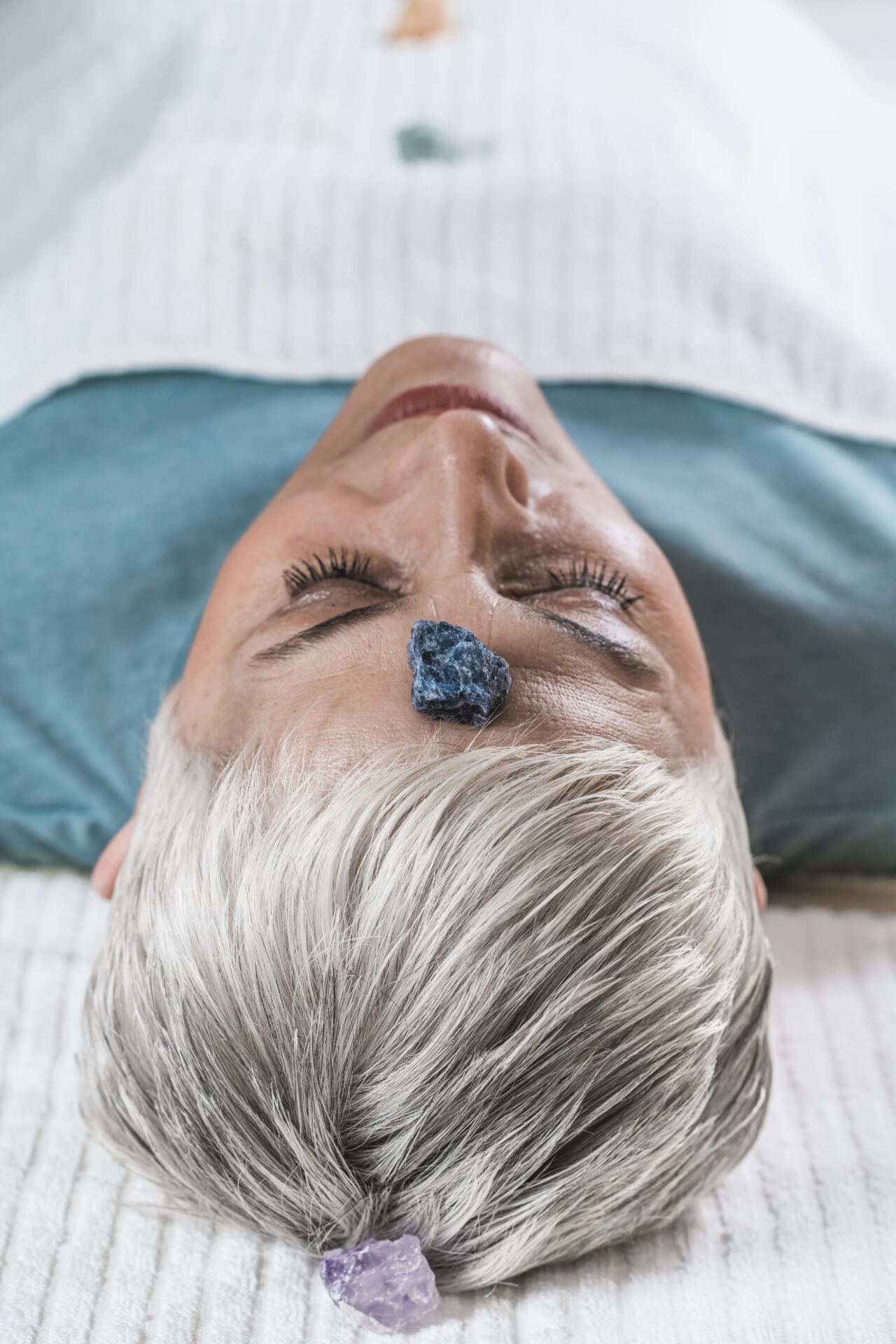 Healing and Balancing Chakras Therapy. Beautiful elderly woman lying on massage table and enjoying chakra healing treatment